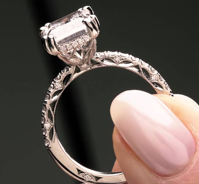 Close-up of dantela engagement ring held between fingers