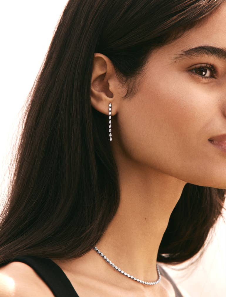 Female model posing with Stilla drop earrings and diamond necklace