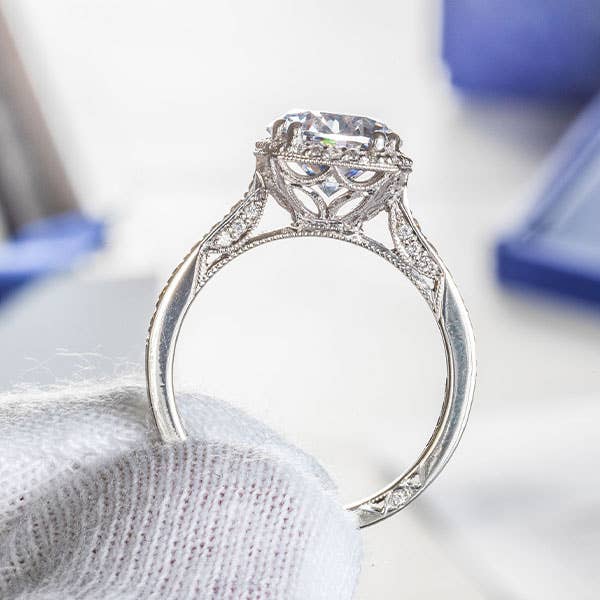 White gloved hand holding a TACORI engagement ring in close up